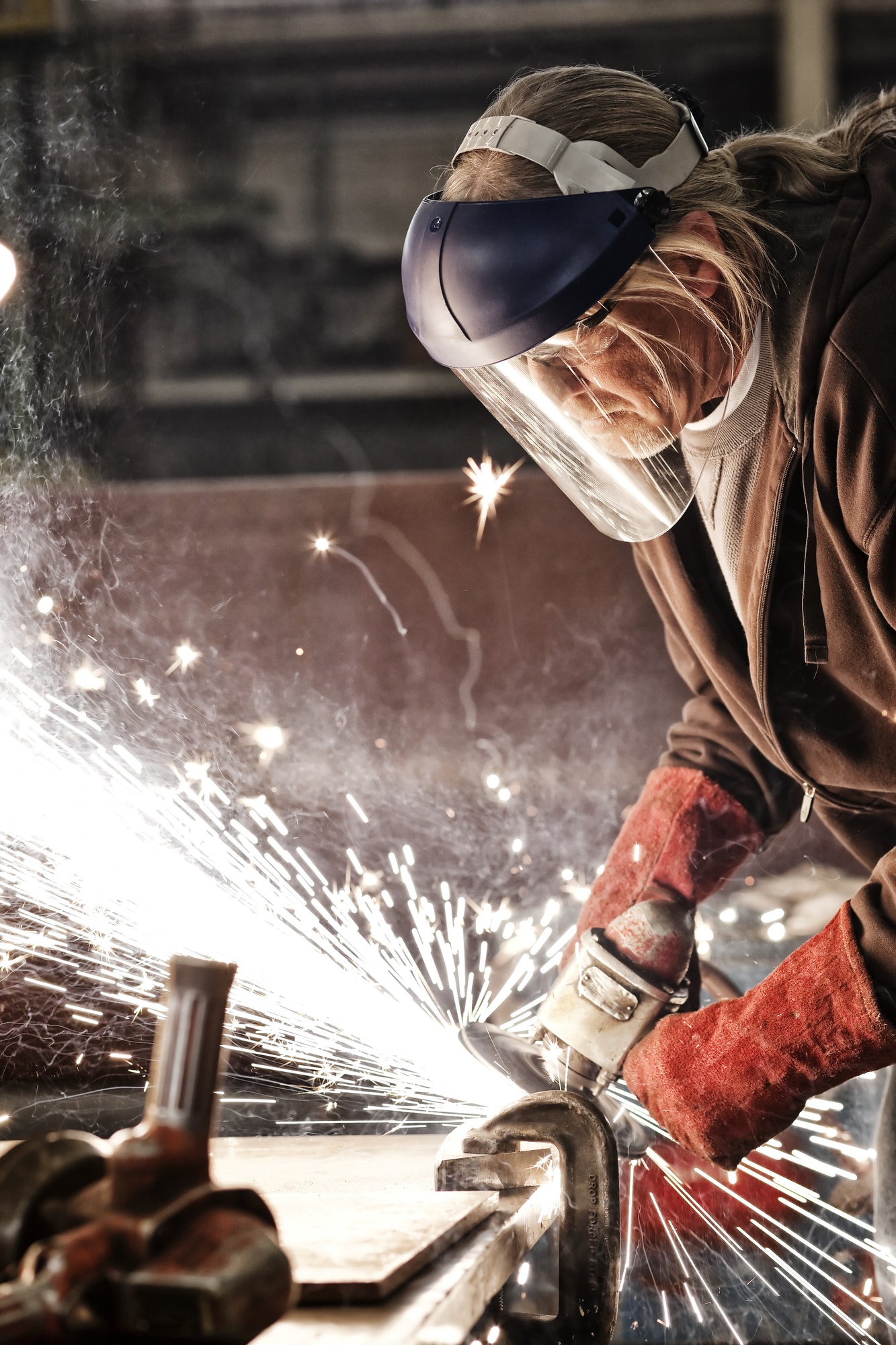 factory worker grinding a steel edge in a sheet metal factory